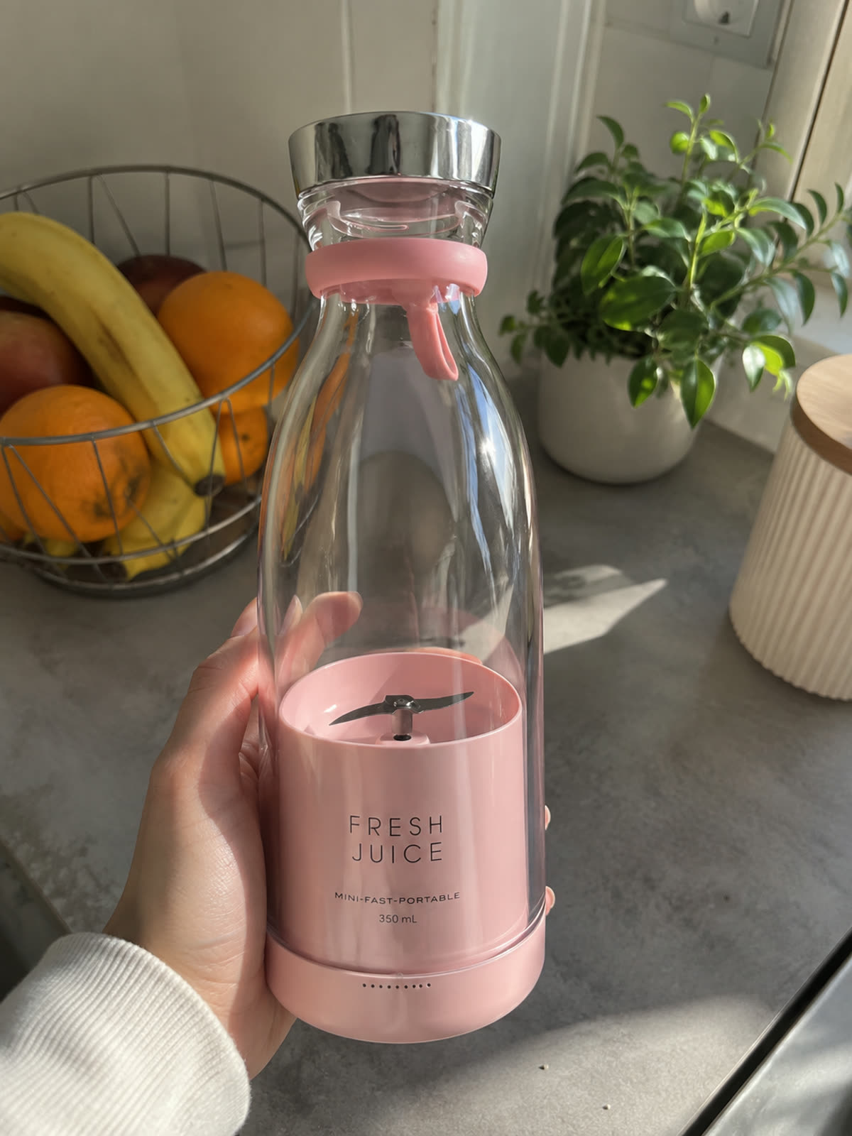 Blender portable rose vide tenu en main, lames visibles au fond de la bouteille